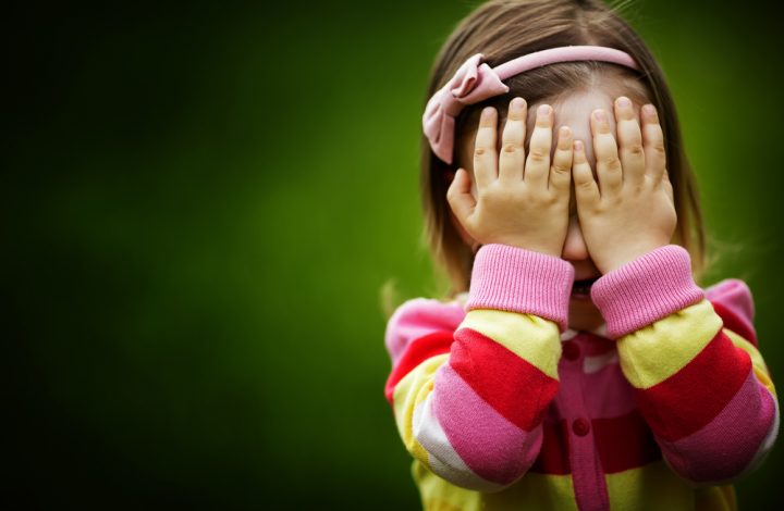 photo of young girl covering her eyes with her hands