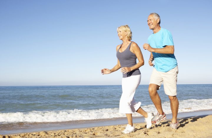 photo of older couple running on beach